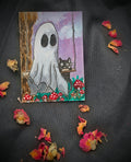 Original Ghost and Kitty ACEO painting featuring a white ghost, black cat on a swing, and red mushrooms, photographed on black fabric with dried rose petals.