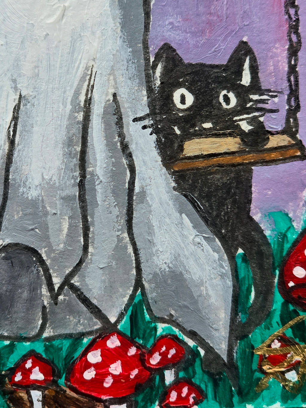 Close-up of a hand-painted white ghost, black cat on a wooden swing, and red spotted mushrooms in A Little Life After Death.
