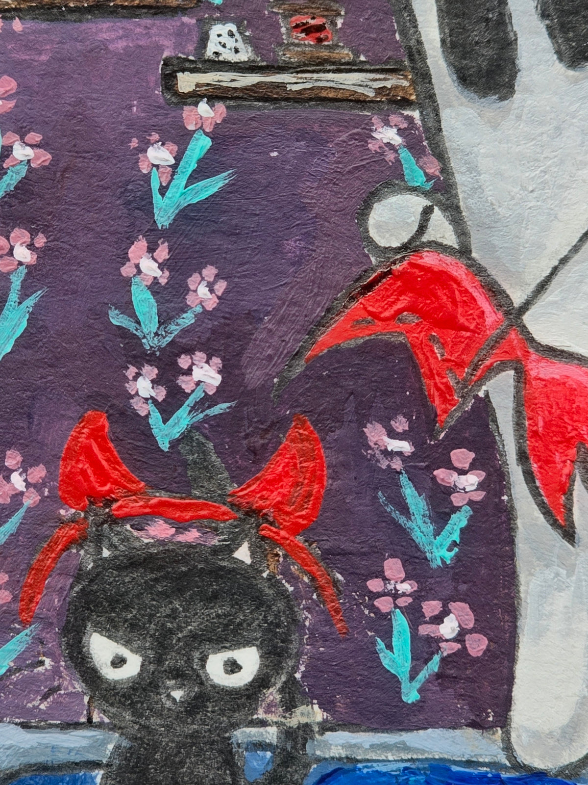 Close-up of A Little Devil in the Making showing a black kitten wearing bright red devil horns beside a ghost holding red fabric, against a purple patterned background.