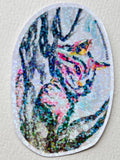 Between The Branches 3-inch vinyl sticker featuring a colorful cat nestled among tree branches
