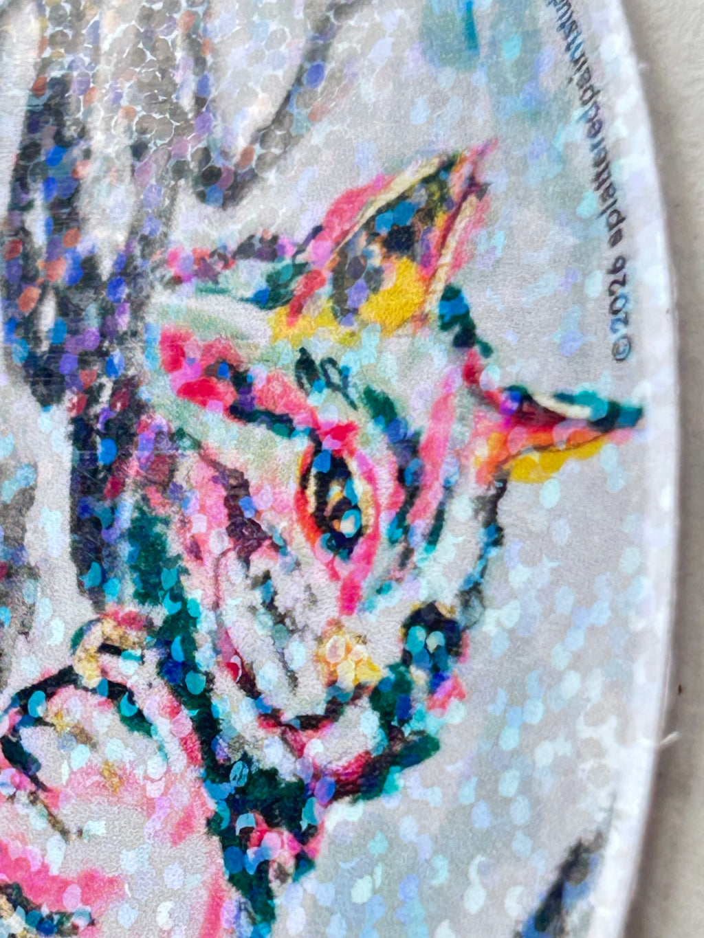 Close-up of Between The Branches vinyl sticker showing the colorful cat face and water-resistant finish