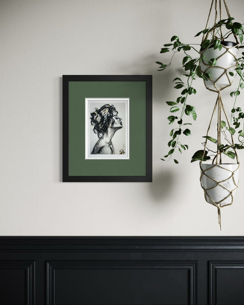 Breath of Light 5x7 charcoal art print with gold accents displayed in a black frame with green matting