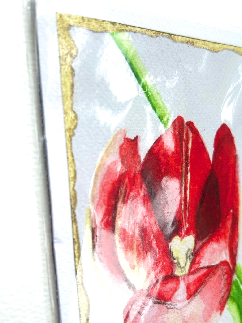 Angled detail of Ember in Bloom 5x7 art print showing the red flower, green stem, and hand-painted gold border