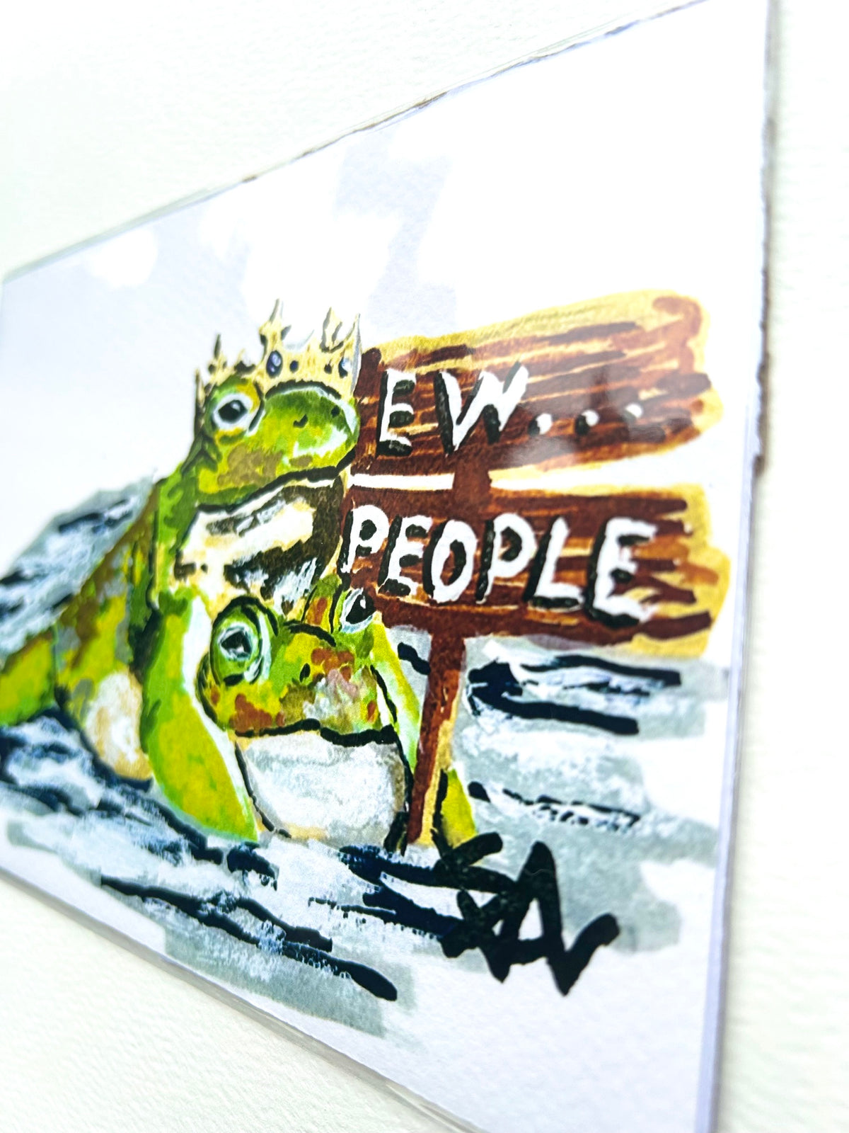 Angled close-up of Ew...People 5x7 art print showing the crowned frogs and wooden Ew People sign