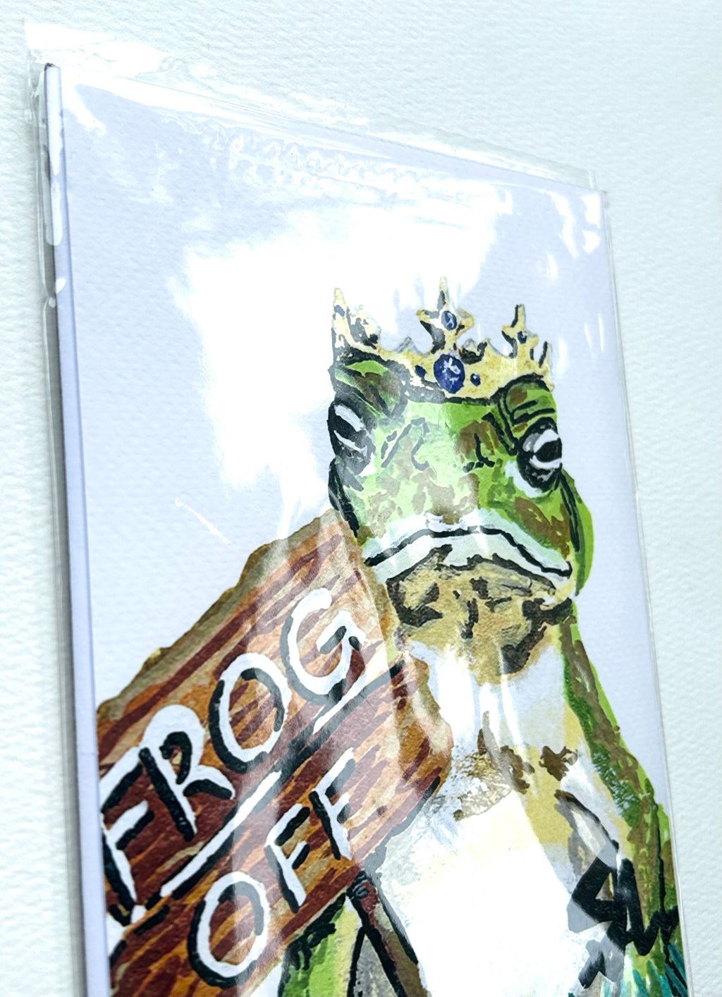 Frog Off 5x7 art print featuring a crowned green frog shown inside its protective clear packaging