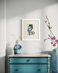 Golden Defiance 5x7 charcoal art print displayed in a white frame above a blue dresser
