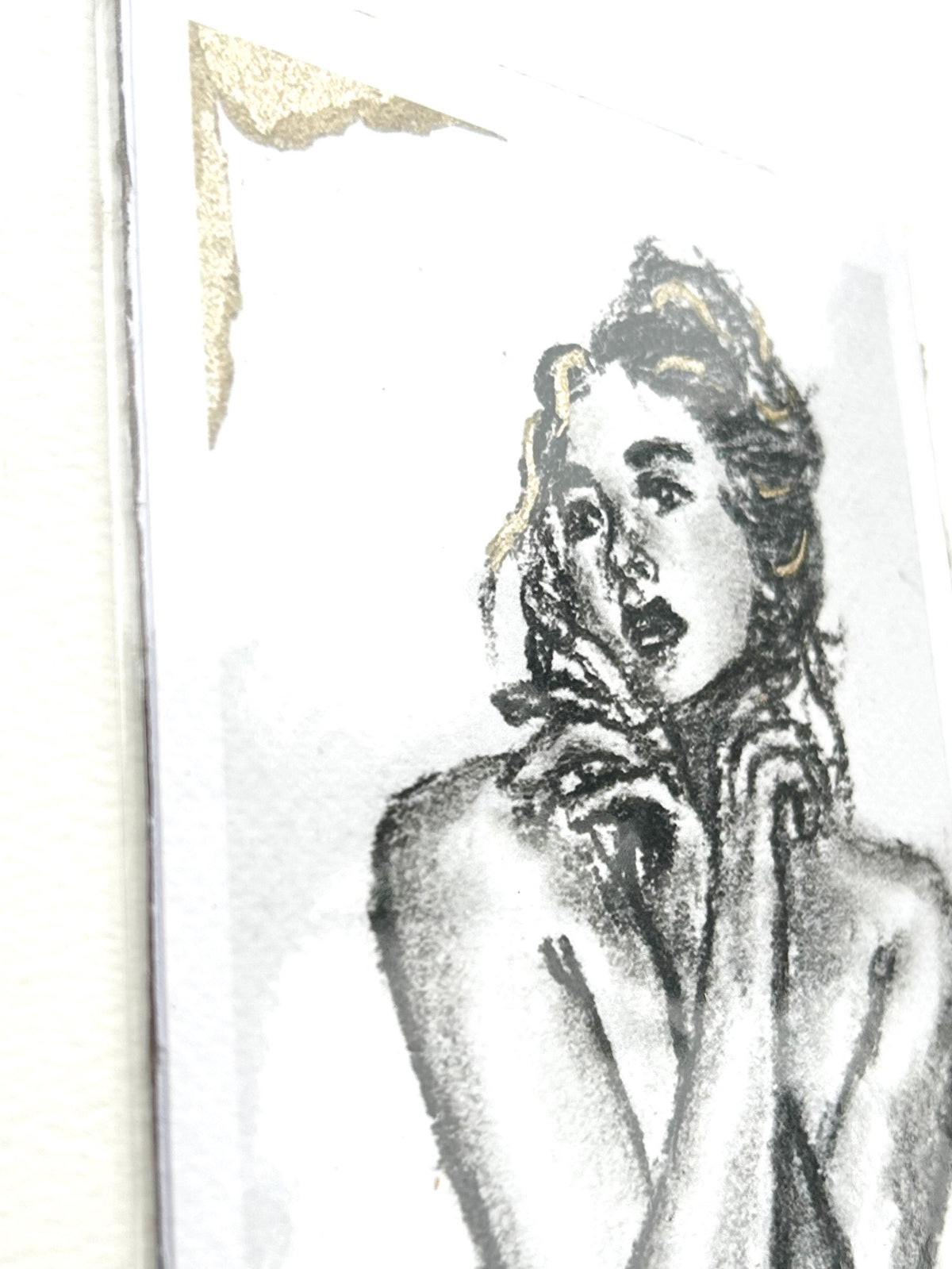 Angled close-up of Held Breath 5x7 charcoal art print showing the expressive female figure and gold accents
