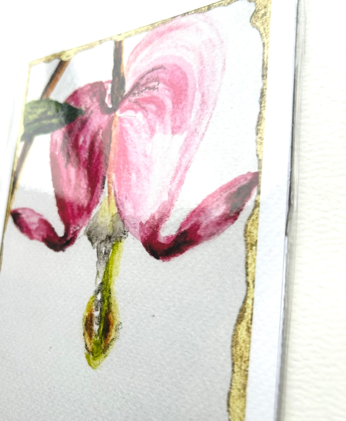 Angled view of Kindred Hearts 5x7 art print showing the pink bleeding heart flower, gold border, and paper texture