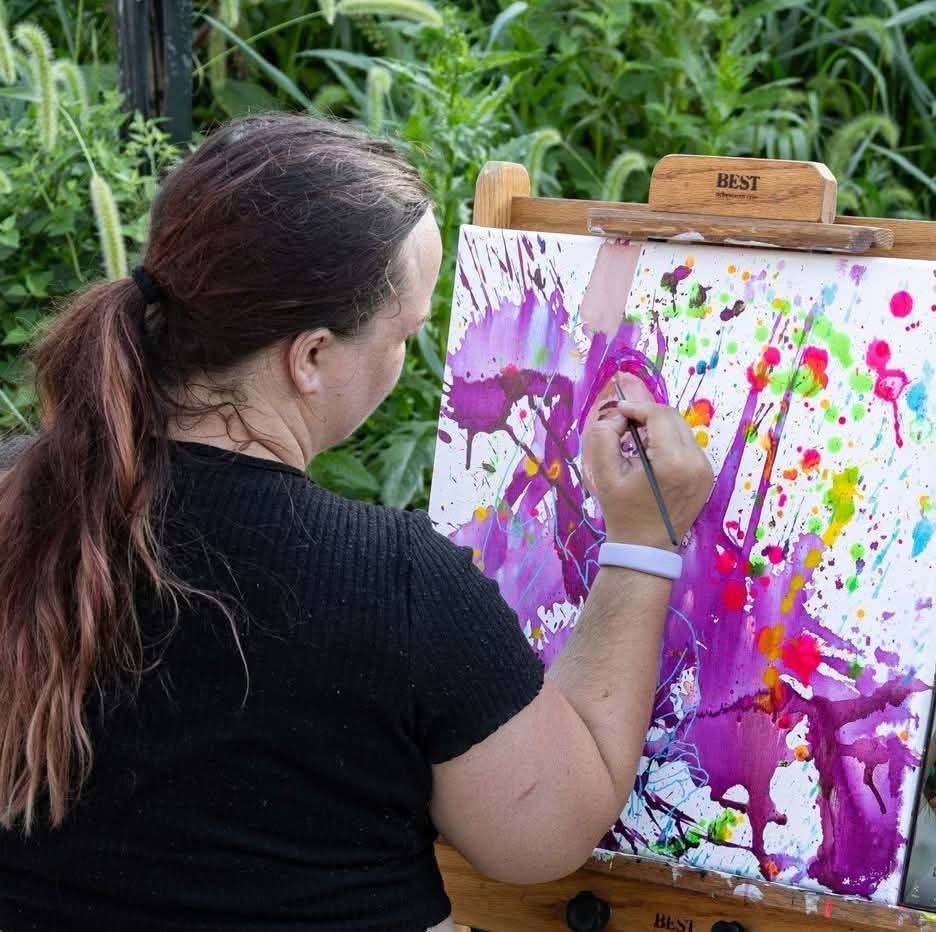 Artist creating a colorful live painting outdoors at an event
