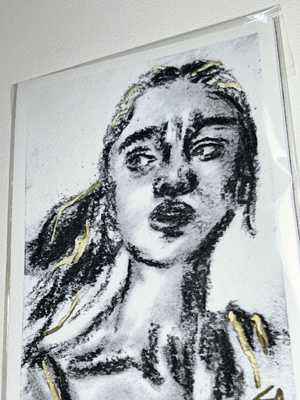 Close-up of Looking Back charcoal art print showing an expressive portrait with gold accents
