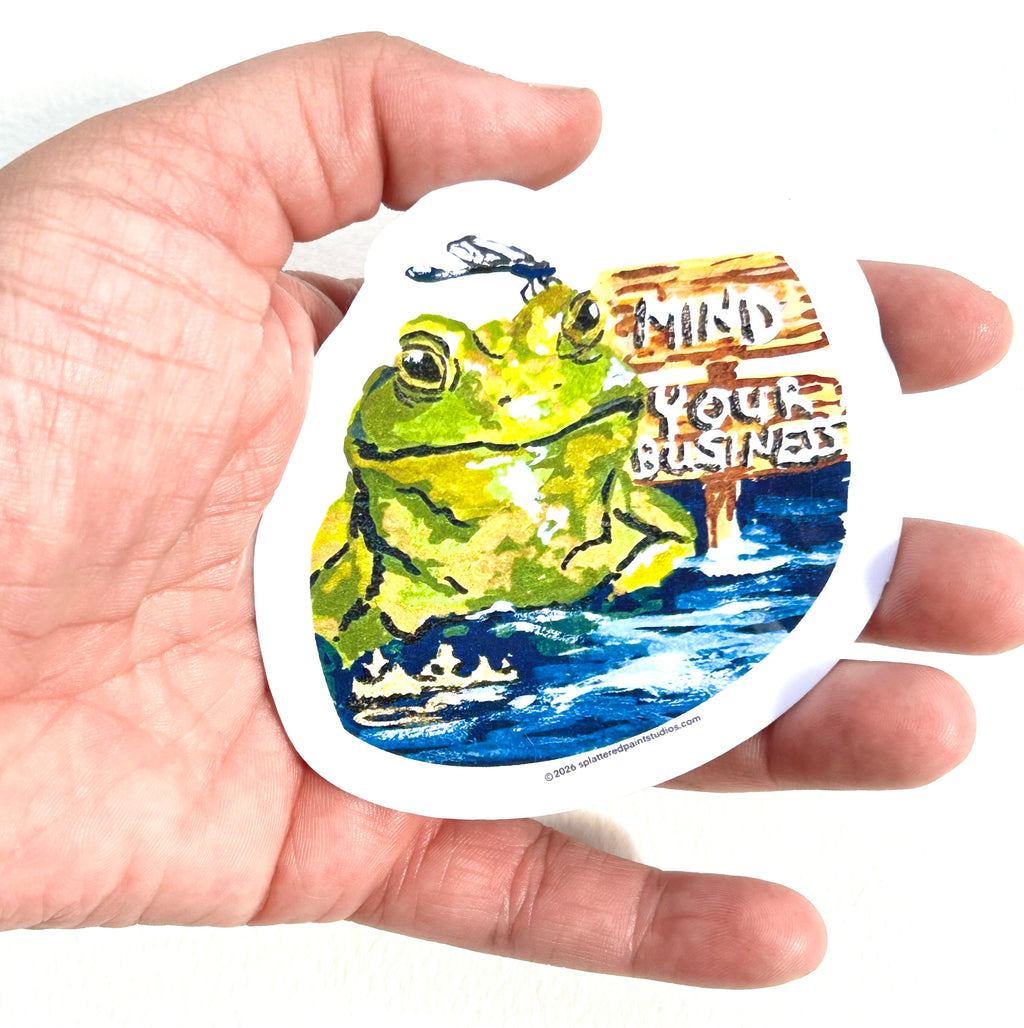 Mind Your Business 3-inch vinyl frog sticker held in hand to show size and scale