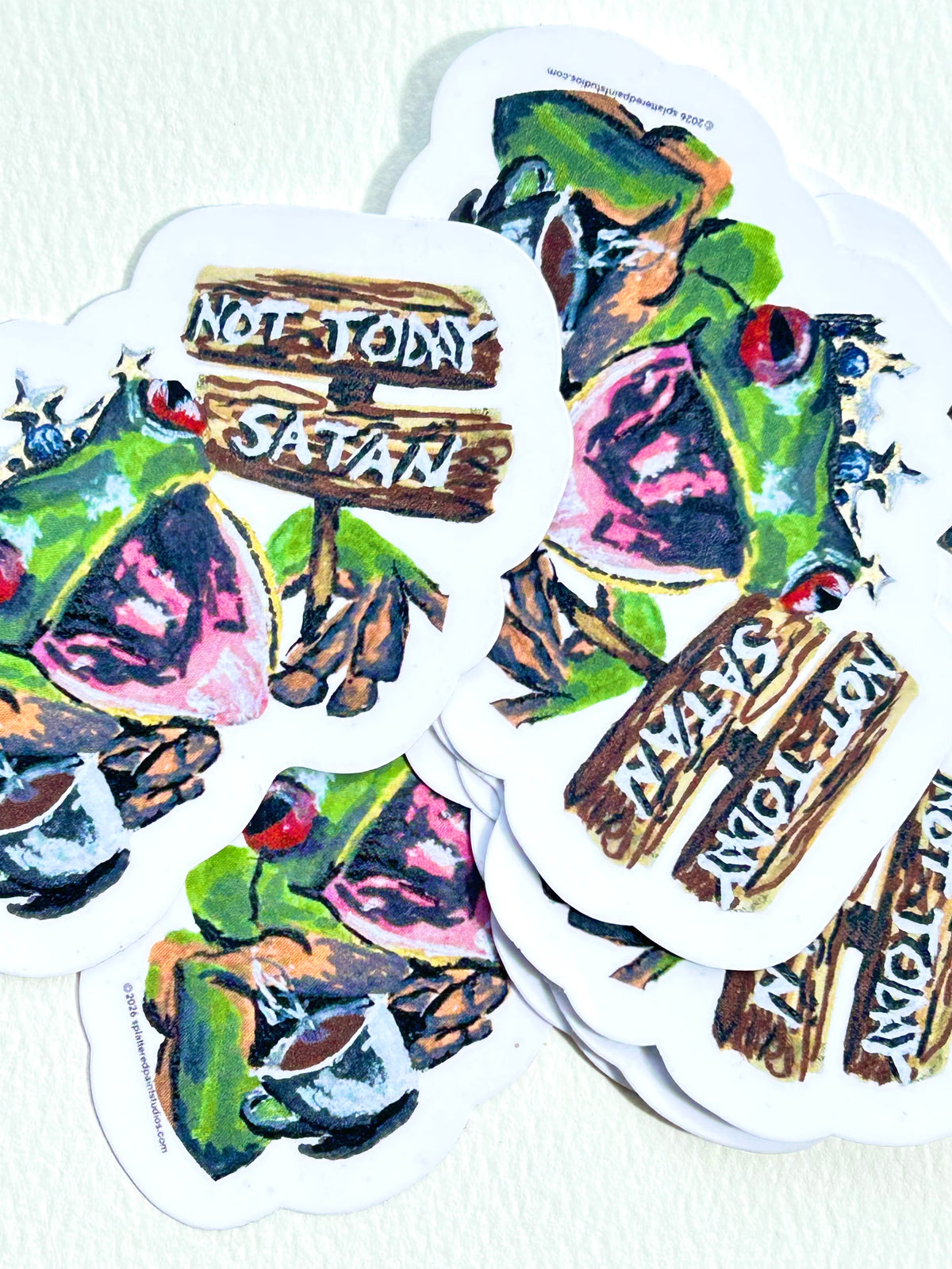 Stack of Not Today Satan vinyl stickers featuring a crowned green frog holding a wooden sign