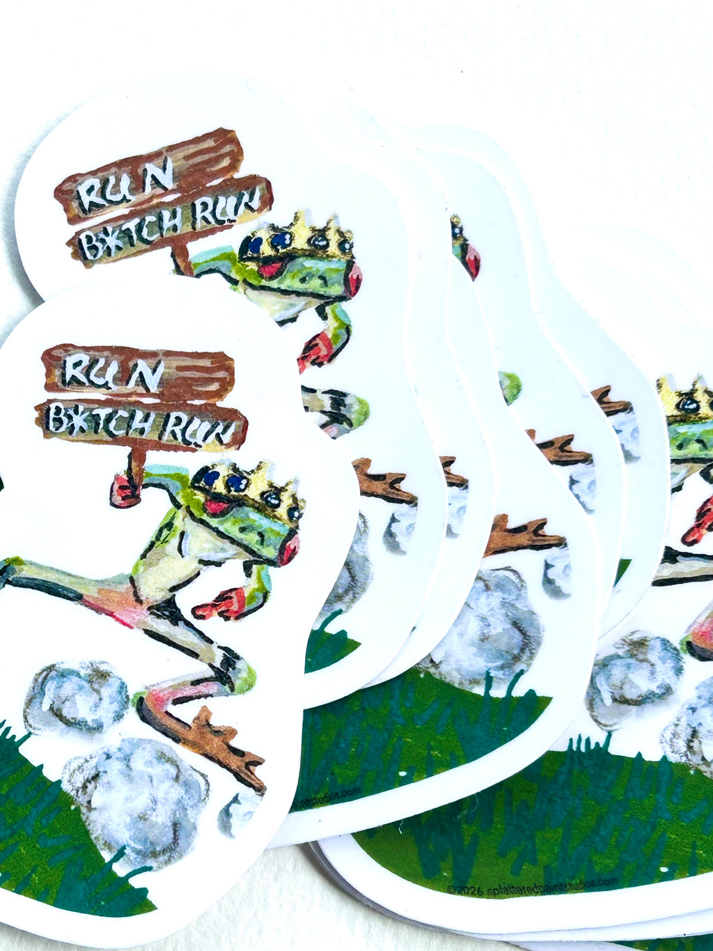 Stack of Run B*tch Run vinyl stickers featuring a crowned frog running with a wooden sign