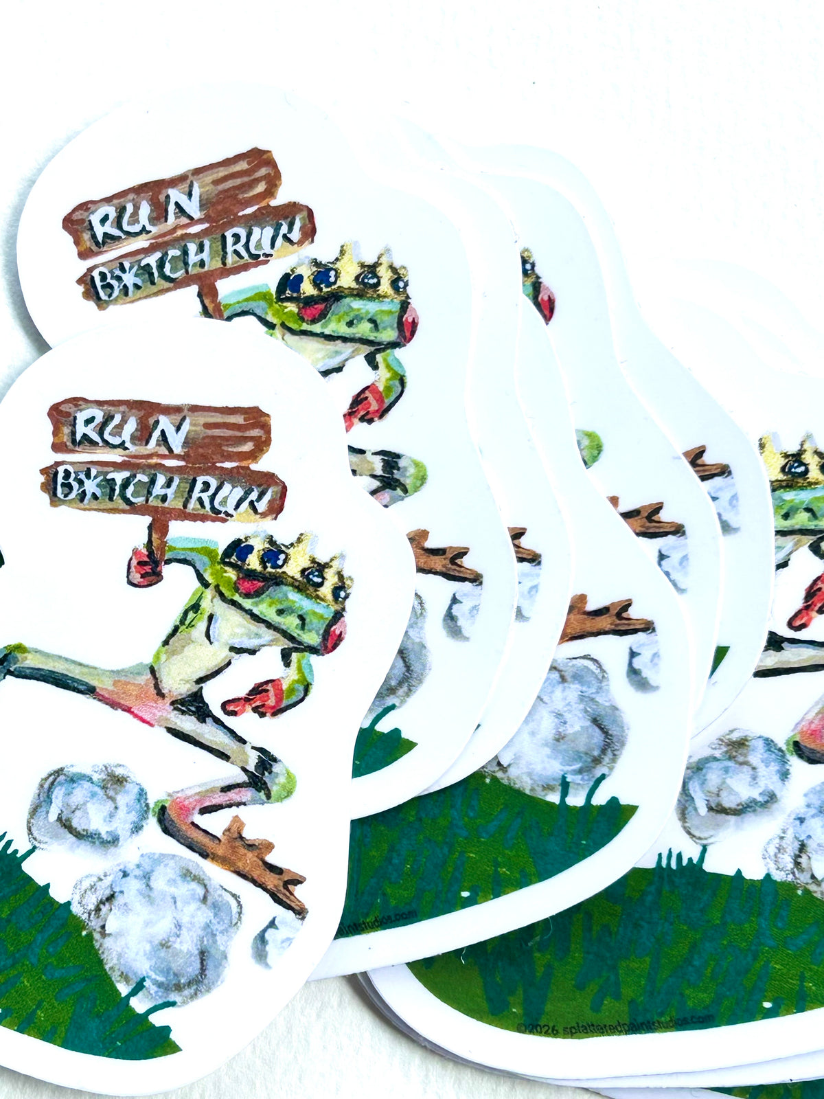 Stack of Run B*tch Run vinyl stickers featuring a crowned frog running with a wooden sign