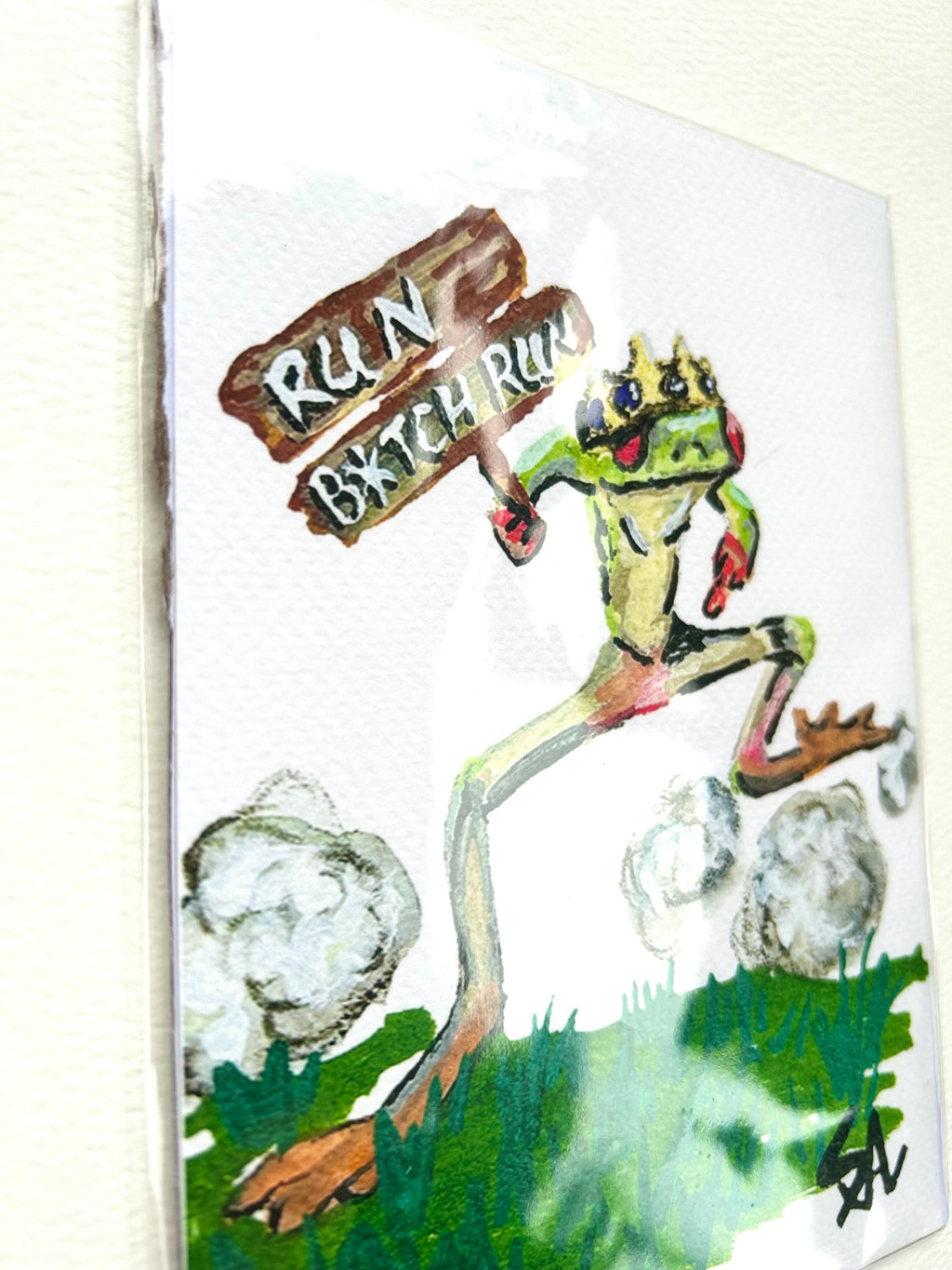 Angled detail of Run B*tch Run 5x7 art print showing a crowned green frog running with a wooden sign