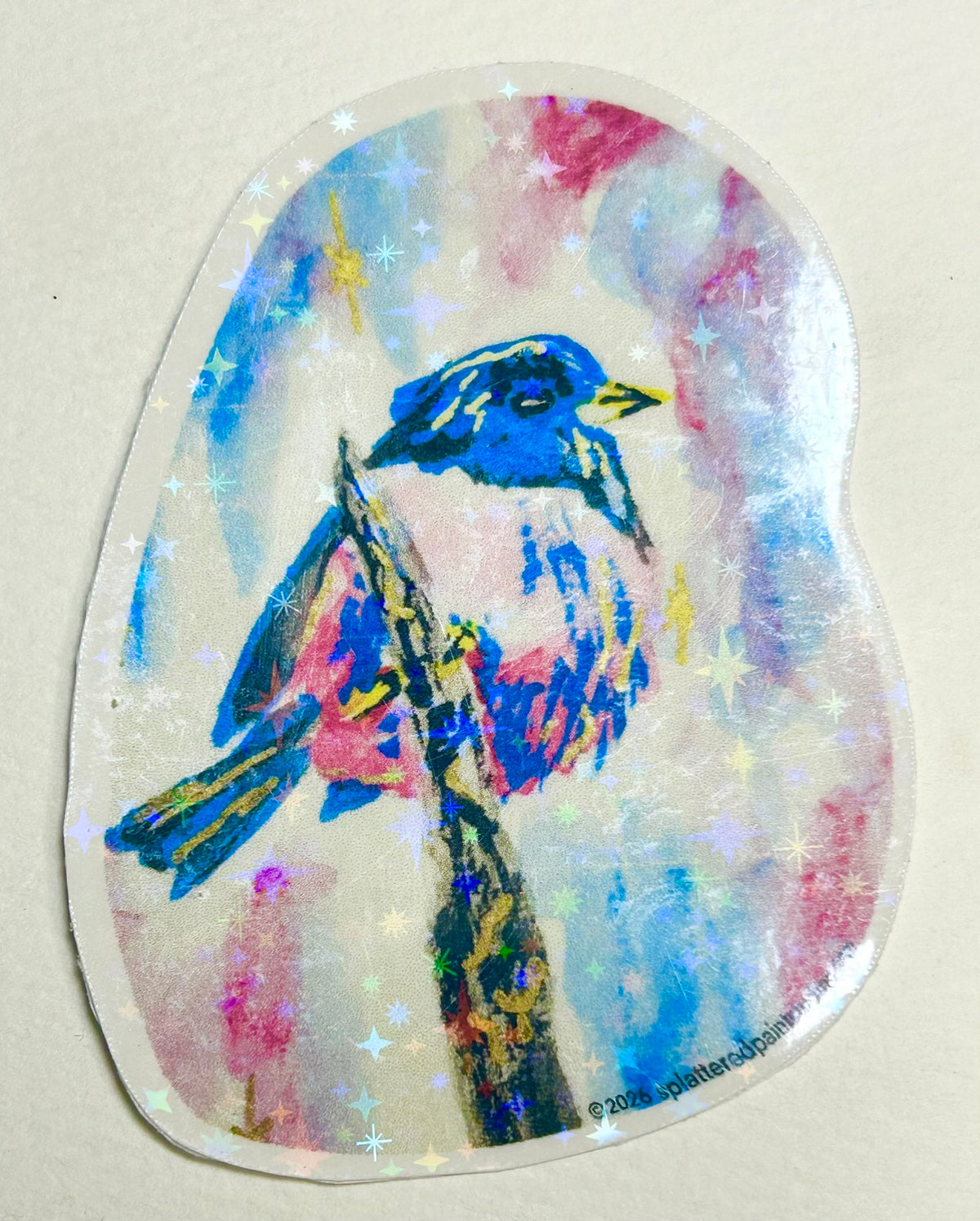 Skyspell 3-inch holographic vinyl art sticker featuring a colorful blue and pink bird perched on a branch