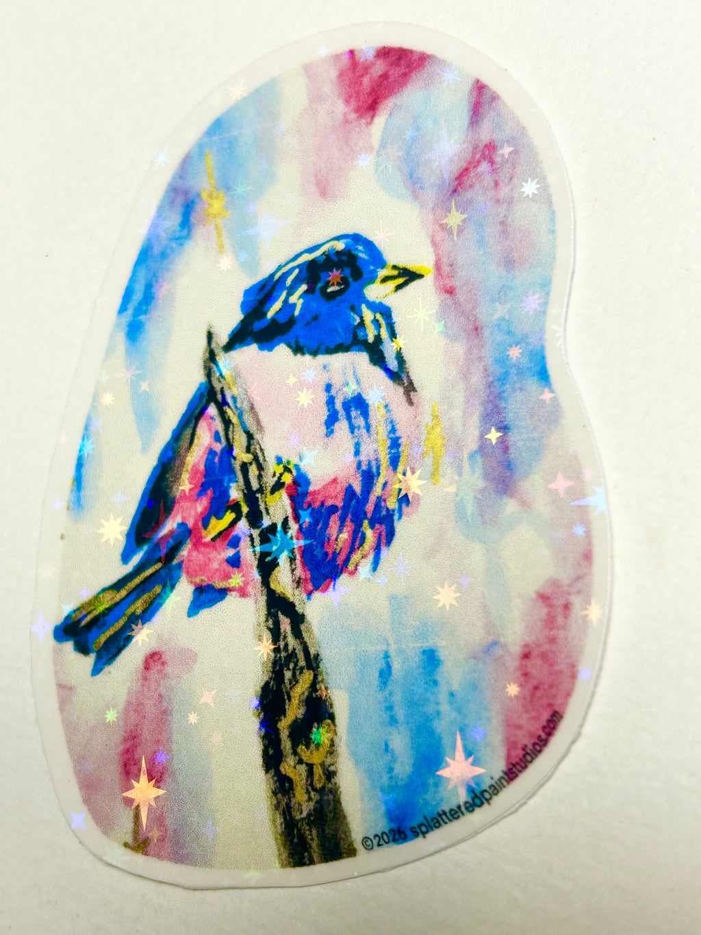 Full view of Skyspell 3-inch holographic vinyl sticker featuring a colorful blue and pink bird with reflective star accents