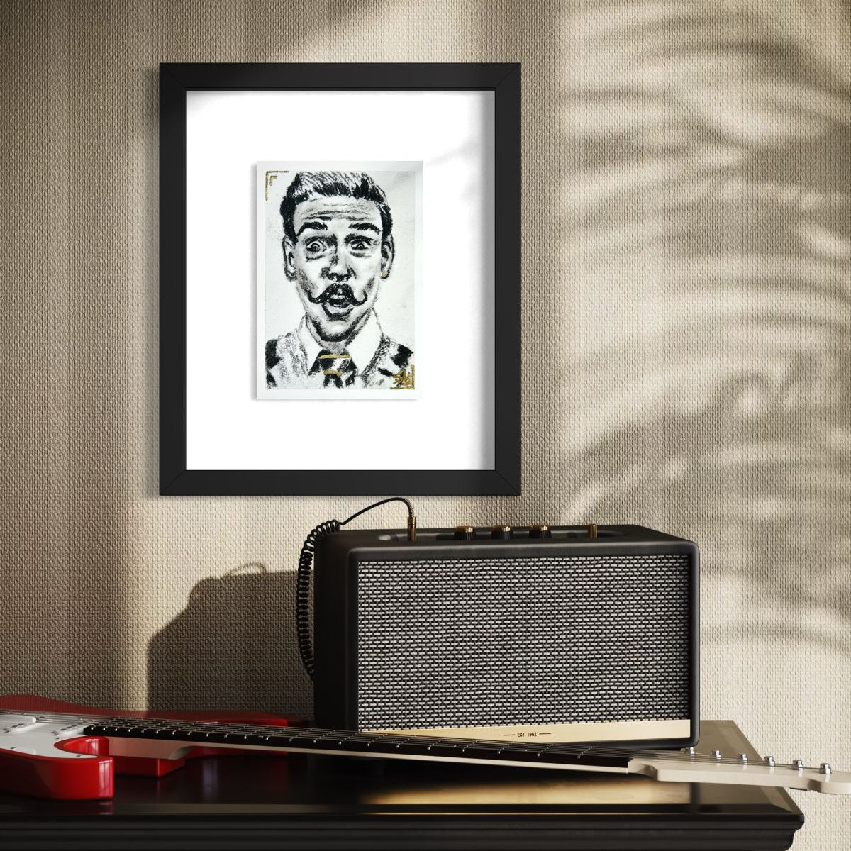 The Showman expressive black and white portrait art print with gold accents displayed in a black frame above a guitar amplifier.